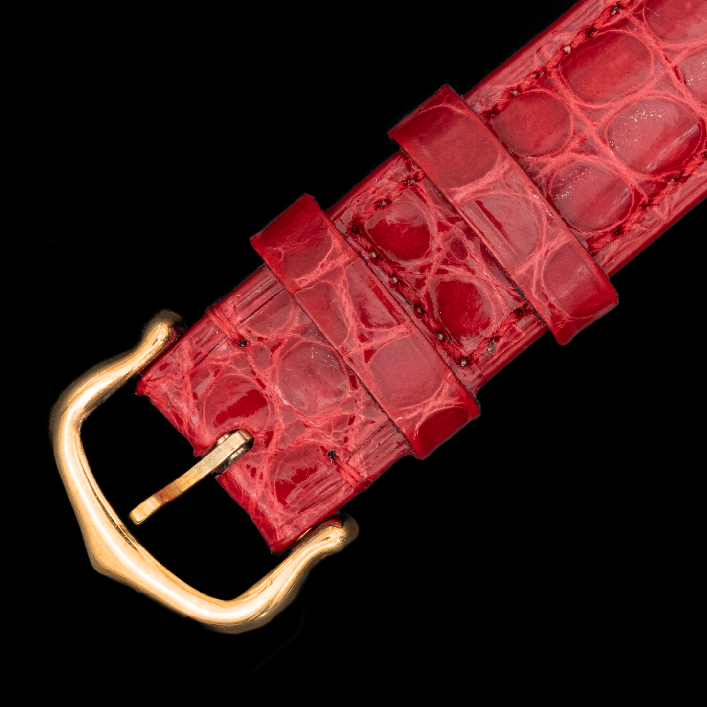 Red textured belt with a gold buckle on a black background