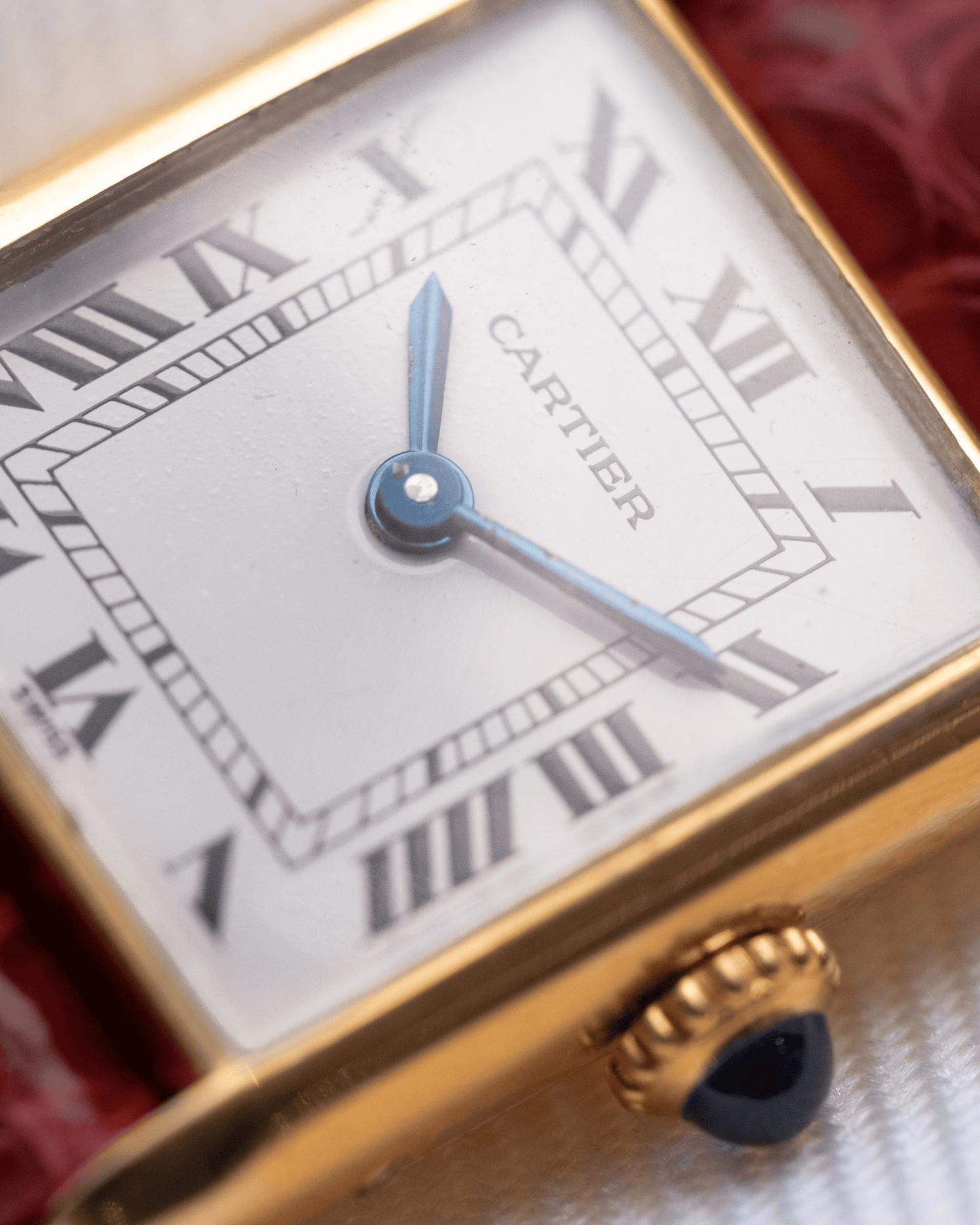 Cartier watch with gold case and white face featuring Roman numerals.