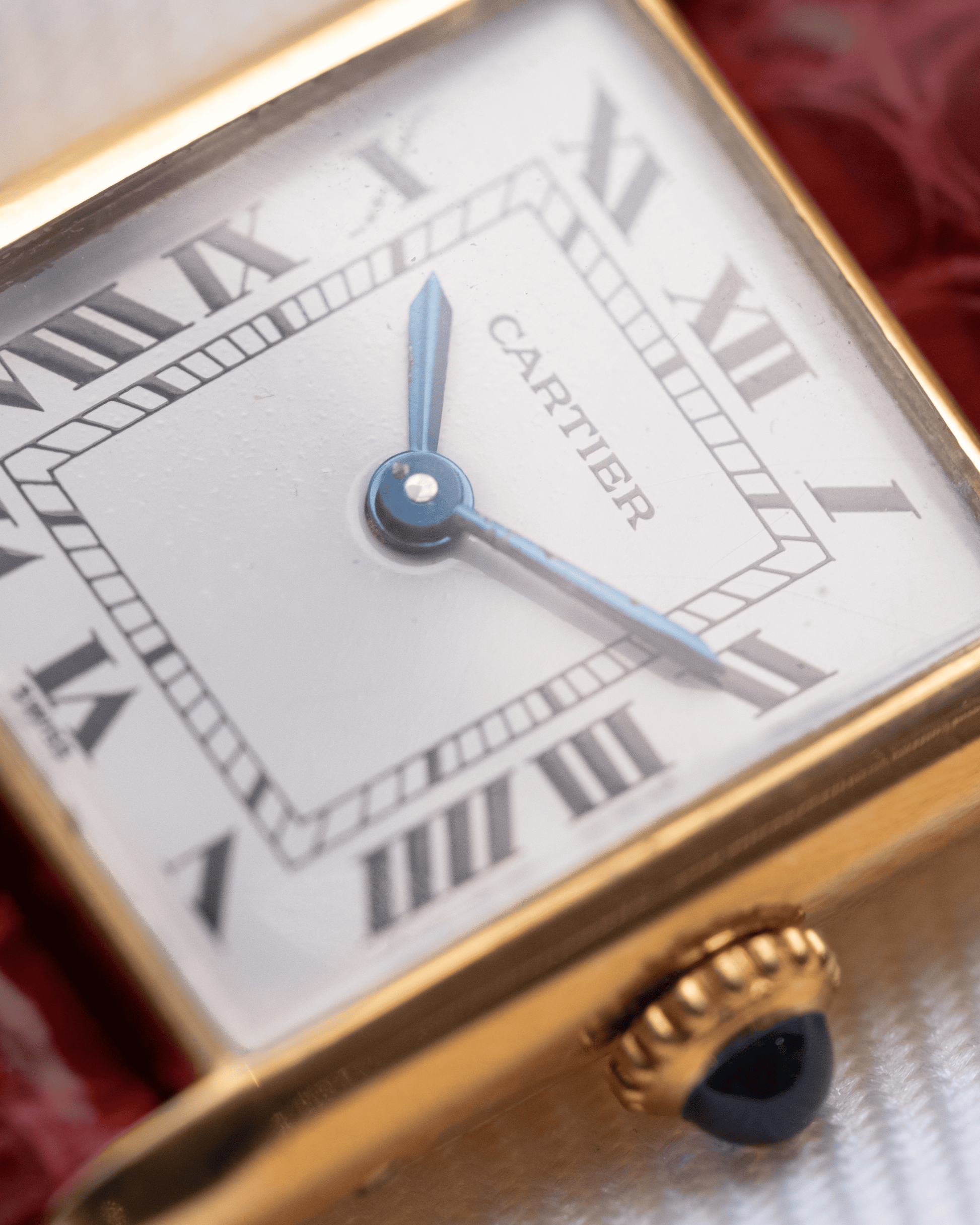Cartier watch with gold case and white face featuring Roman numerals.