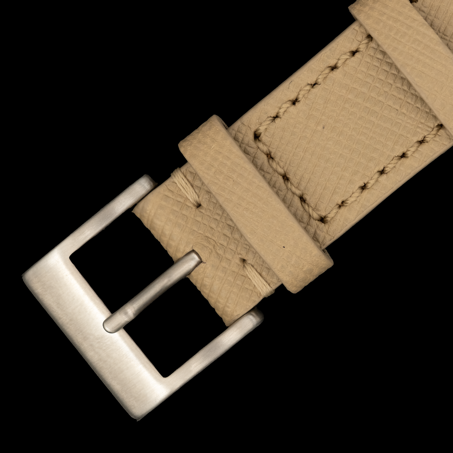 Beige leather watch strap with silver buckle on a black background