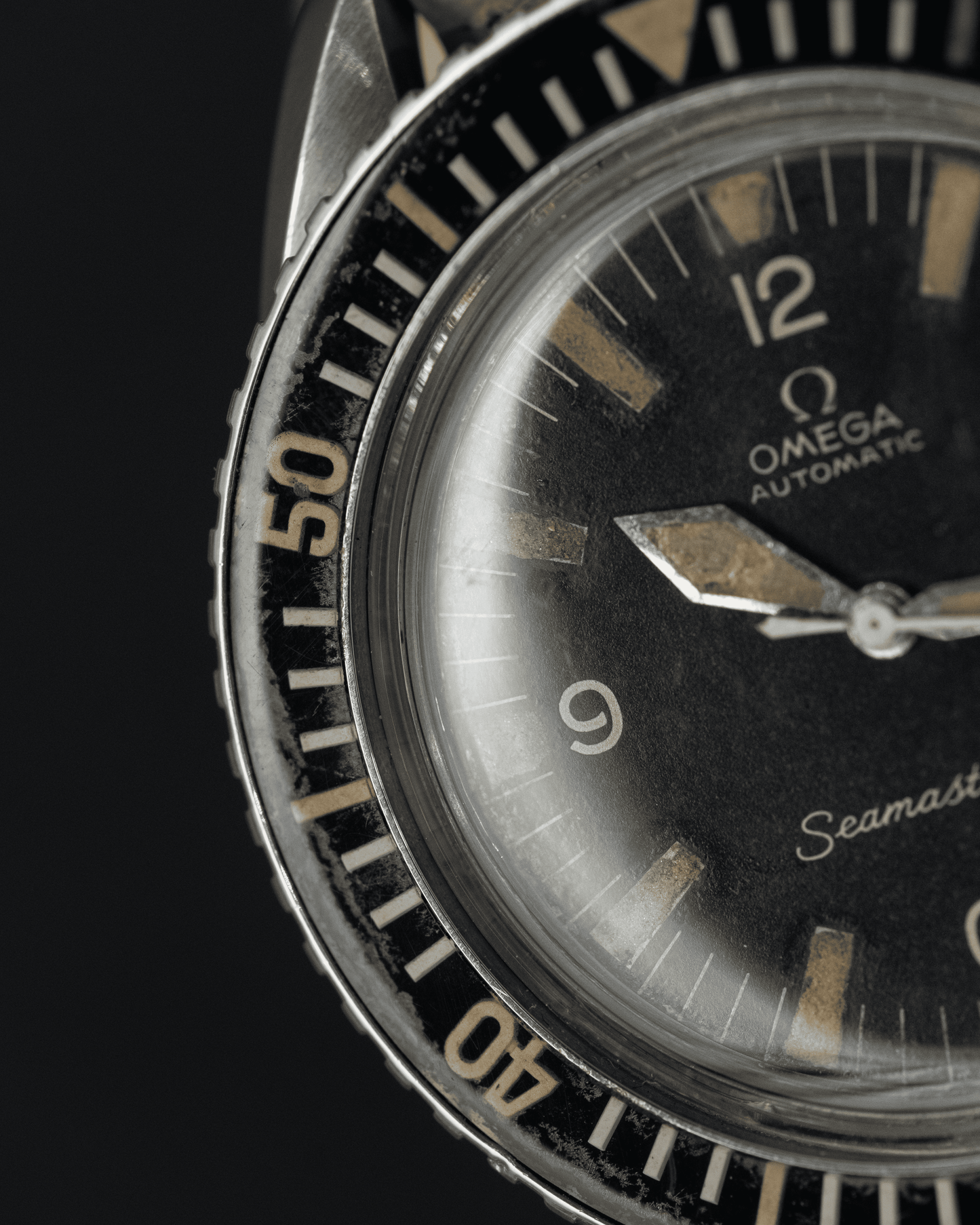 Close-up of an Omega Seamaster watch face with black dial and silver bezel.
