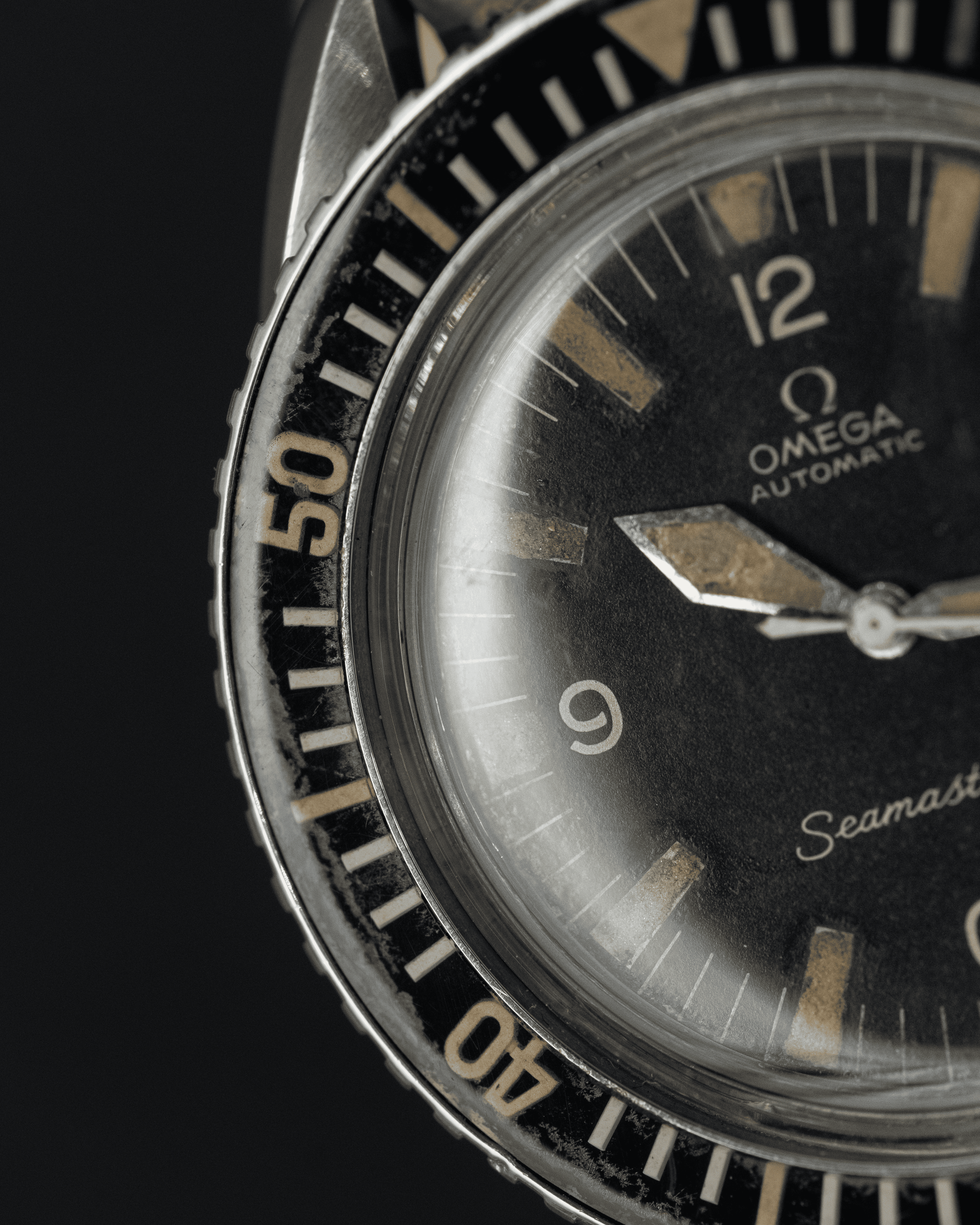 Close-up of an Omega Seamaster watch face with black dial and silver bezel.
